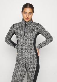 Čierny a šedý zip-up top s geometrickým vzorom, dlhými rukávmi a vysokým golierom. Vyrobené z elastickej, textúrovanej tkaniny pre pohodlie.