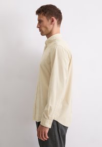 Lichtgele corduroy shirt met een button-down kraag, lange mouwen en een rechte snit. Getextureerde stof met subtiele verticale lijnen.