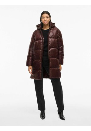 Cappotto imbottito bordeaux con cappuccio regolabile, design imbottito oversize, zip frontale e tasche laterali. Abbinato a un top e pantaloni neri.