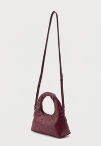 Burgunderfarvet læderhåndtaske med et rundt håndtag og justerbar rem, der har en quilted tekstur med geometriske mønstre.