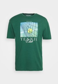 Grön bomull T-shirt med rund halsringning, prydd med en tryckt grafisk bild av en tennisboll och nät, med texten "TENNIS Klubb" nedanför.