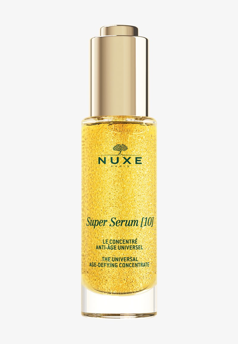 Bottiglia di Nuxe Super Serum con microperle dorate e tappo dorato, etichettata come concentrato universale anti-età.