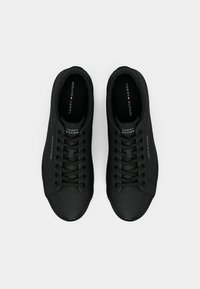 Paire de baskets noires Tommy Hilfiger avec lacets, vues de dessus sur un fond clair uni.
