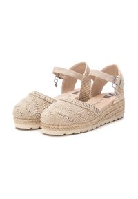 Zapatos estilo espadrille en color beige con tejido trenzado, puntera redonda, correas en el tobillo y detalles de yute trenzado en una suela plana.