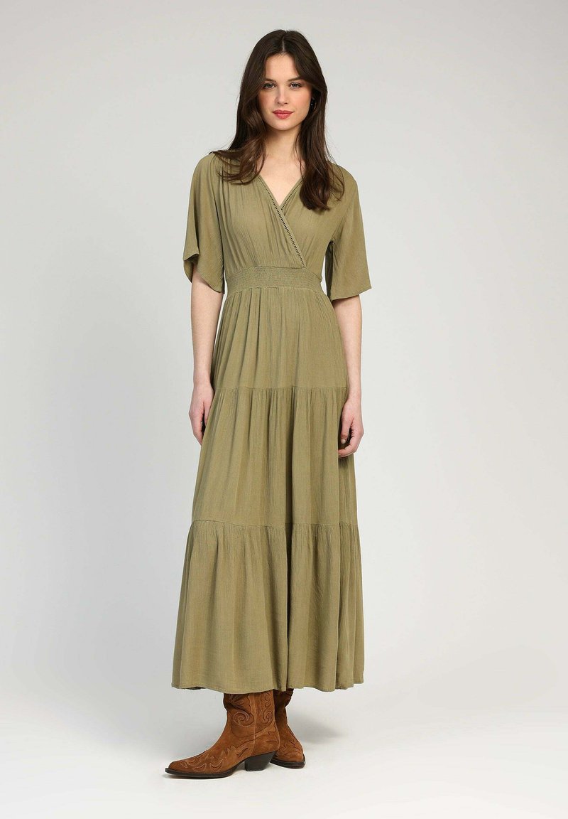 Robe maxi vert olive, jusqu'aux genoux, avec des manches volantées, un col en V et une jupe à volants. Assortie à des bottes de cowboy marron ornées de broderies.