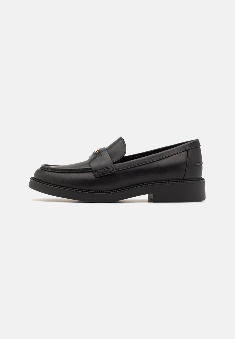 Black leather loafers with a stitched trim, flat rubber sole, and a decorative strap across the vamp; smooth texture and minimal design.