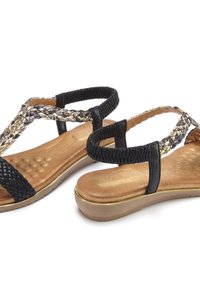 Schwarze und goldene geflochtene Slingback-Sandalen mit einem strukturierten schwarzen Riemen und einer gepolsterten, tanfarbenen Innensohle, die eine niedrige Plattformsohle aufweisen.