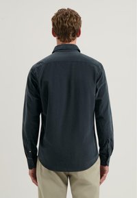 Donkergroene blouse met lange mouwen, button-down kraag, plooien aan de achterkant en verstelbare manchetten. Gemaakt van soepele katoenen stof.