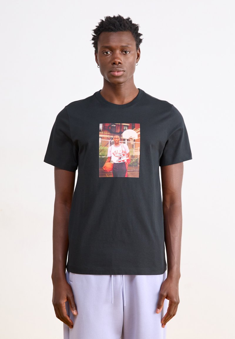 Schwarzes Baumwoll-T-Shirt mit einem zentralen Grafikmotiv eines Basketballspielers. Kurze Ärmel, runder Halsausschnitt, glatte Textur.