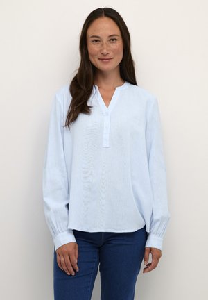 Chemise bleu clair à manches longues avec un col en V et une fermeture à boutons. Texture douce, coupe décontractée et détails plissés sur les manches.