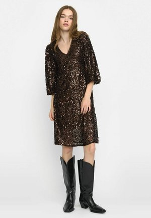Brown sequin dress with a V-neck and loose sleeves, featuring a knee-length cut. Model wears black cowboy boots as footwear.