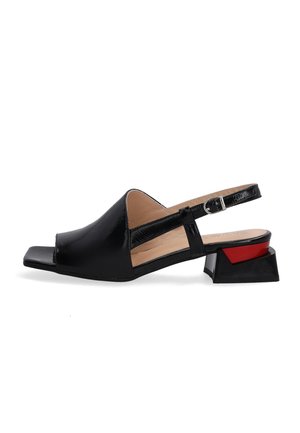 Black patent leather slingback shoes with an open toe, block heel featuring a red accent, and a sleek, modern design.
