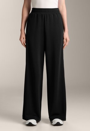 Schwarze weit geschnittene Hose mit elastischem Bund, aus weichem, leichtem Stoff. Hat eine glatte Textur und reicht bis zum Knöchel.