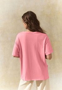Übergroßes rosa Baumwoll-T-Shirt mit kurzen Ärmeln und rundem Ausschnitt, mit leicht geschwungem Saum und lockerem Sitz.