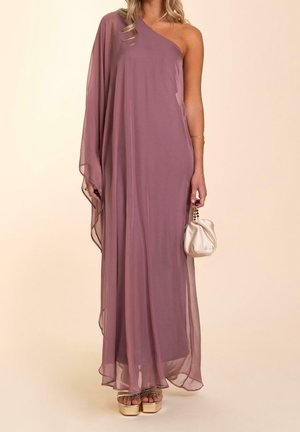 Donna che indossa un abito color malva monospalla trasparente, che tiene una piccola pochette in raso, abbinata a sandali platform dorati e gioielli minimalisti.