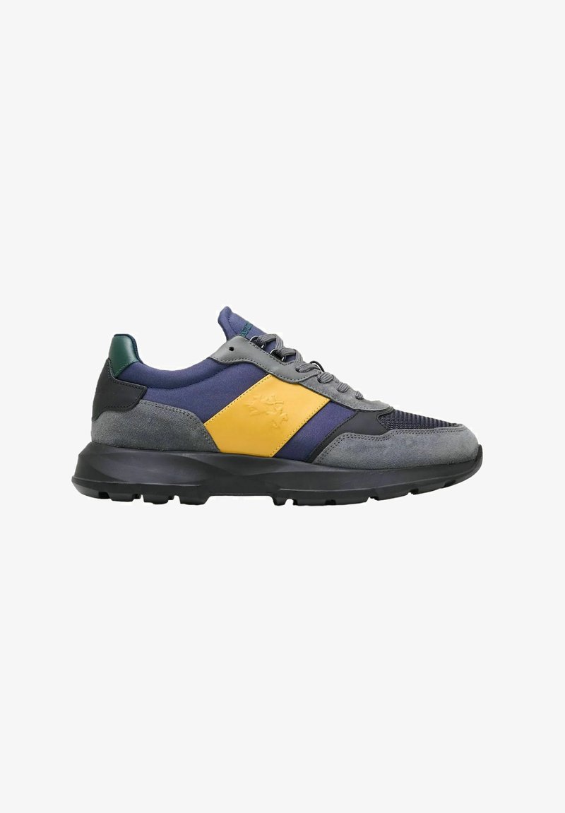 Zapatillas de hombre con parte superior de ante y malla en color gris, detalles en navy y amarillo, y suela gruesa de goma negra. Cuenta con cierre de cordones y cuello acolchado.