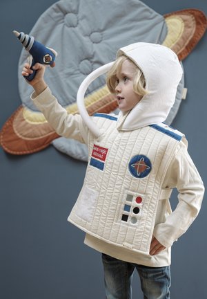 Katoenen astronautenkostuum met doorgestikte crèmekleurige stof, blauwe strepen, rode en blauwe patches, en een witte capuchon. Houdt een speelgoedstraalpistool vast. Achtergrond in grijs.