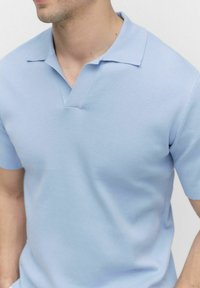 Ljusblå kortärmad polo med krage och textilstruktur, minimalistisk design med en ren skärning.