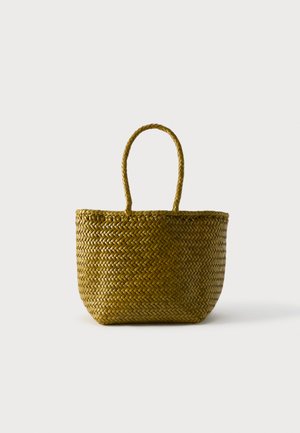 Geweven stro draagtasje met afgeronde bodem en twee lusvormige handvatten, afgebeeld tegen een egale lichte achtergrond.