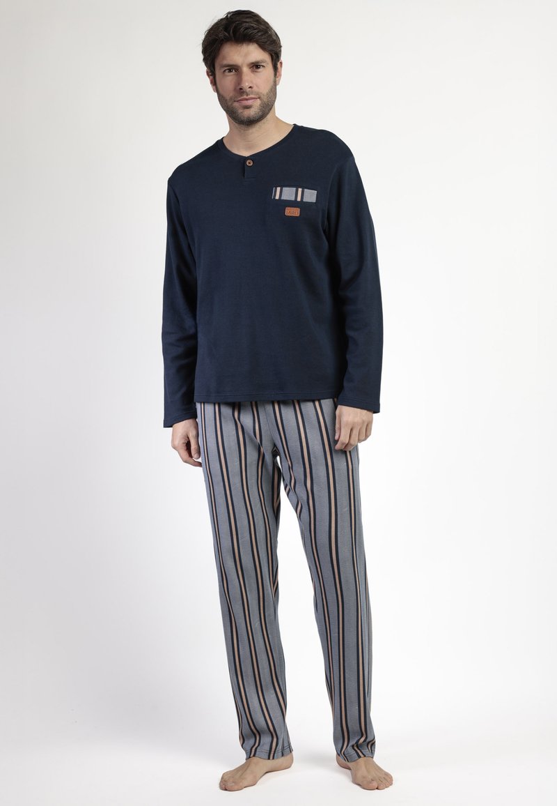 Top de manga larga color marino con un bolsillo en el pecho; pantalones rayados en gris con rayas azules y beige; tejido suave; corte relajado; sin marca visible.