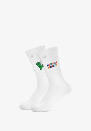 Chaussettes blanches montantes avec un petit dinosaure vert tenant une bougie sur une chaussette et « HAKUNA MATATA » en lettres colorées sur l'autre.