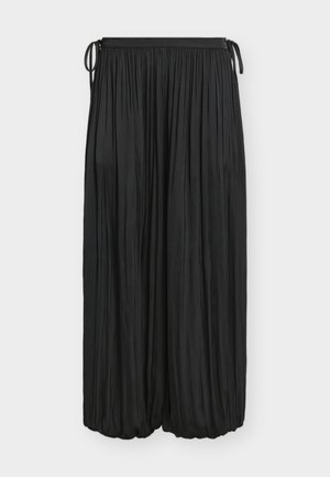 Longue jupe noire plissée avec ourlet élastique froncé et cordons à la taille sur fond blanc.