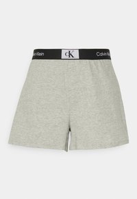 Bóxer de algodón gris con una cinturilla elástica negra que presenta la marca "Calvin Klein" en la parte delantera y en el lateral. Textura suave y corte relajado.