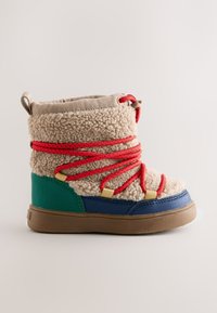 Stivale invernale per bambini con tomaia in pile beige, lacci rossi, dettagli verdi e blu e suola in gomma marrone, mostrato di profilo su sfondo semplice.