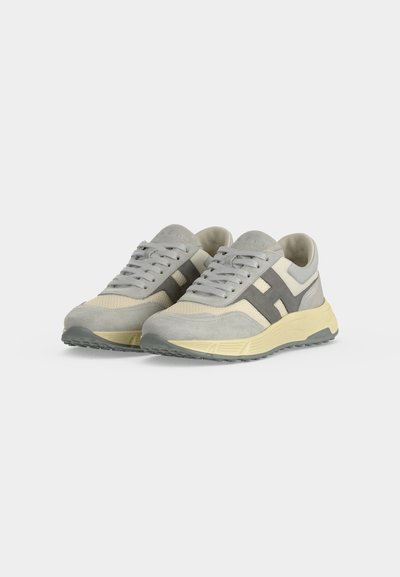 Paire de baskets gris et beige à lacets avec des accents latéraux gris foncé et des semelles claires sur fond blanc.