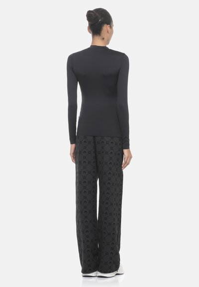 Top a maniche lunghe nero abbinato a pantaloni larghi neri con motivo. Il tessuto ha una trama liscia e dettagli di design sottili.
