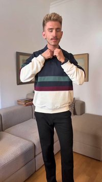 Navy and cream sweatshirt with horizontal stripes in green and maroon, featuring a polo collar, worn with black pants, standing indoors.