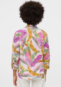 Long-sleeve shirt featuring a colorful leaf pattern in pink, green, yellow, and purple; lightweight fabric with a relaxed fit and shirt collar.