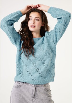 Pull en tricot bleu clair avec un design texturé à motif ondulé, doté d'un col rond et de manches longues.