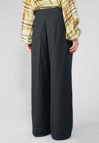 Weite Hosen in Dunkelgrau, gefertigt aus strukturiertem Rippstoff. Entworfen mit hoher Taille und klaren Falten für einen maßgeschneiderten Look.
