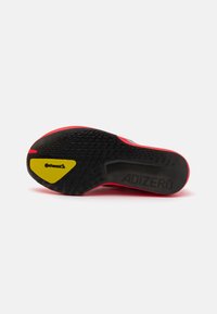 Čierna a červená podrážka topánky s textúrovaným vzorom. Obsahuje žlté logo Continental a v čiernej farbe vyrazený nápis "ADIZERO".