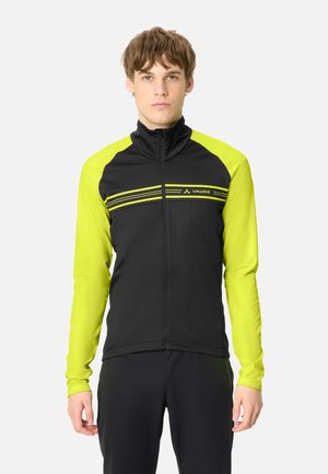 Junger Mann trägt eine schwarze und neon-gelbe Sportjacke mit Reißverschluss, horizontalen Streifen und dem Vaude-Logo auf der Brust.