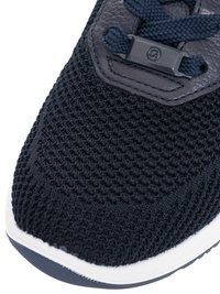 Nahaufnahme der Vorderseite eines schwarzen, gestrickten Sneakers mit marineblauen Schnürsenkeln und Lederösen-Überzug auf weißer Sohle.