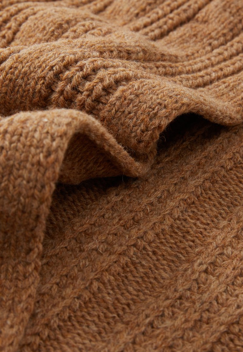 Strikket, brunt tekstil med et struktureret mønster, der har hævede striber og en blød, fuzzet overflade, velegnet til tøj eller accessories.