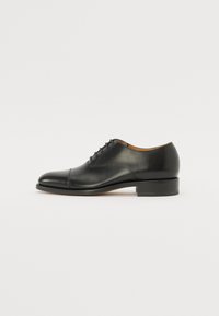 Zapato oxford de cuero negro con un acabado suave, puntera redondeada, cordones cerrados y tacón estrecho. Diseño minimalista sin patrones visibles.