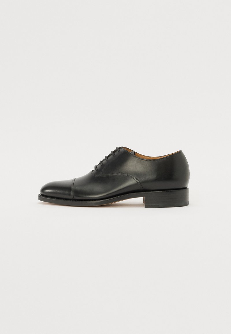 Zapato oxford de cuero negro con un acabado suave, puntera redondeada, cordones cerrados y tacón estrecho. Diseño minimalista sin patrones visibles.