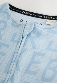 Svetlomodrý látkový top s geometrickým vzorom, zapínaním na gombíky a čiernou etiketou s bielym nápisom "BAKER by TED BAKER".