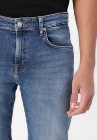 Light blue denim jeans with a straight-leg fit, featuring front pockets, a button closure, and subtle fading.