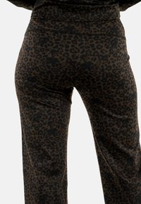 Los pantalones de estampado de leopardo en marrón oscuro y negro cuentan con una cinturilla cómoda y un tejido elástico, adecuados para un uso informal.
