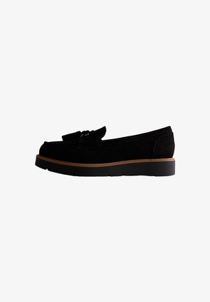 Mocassino in suede nero con rifinitura marrone e suola nera, caratterizzato da un fiocco decorativo sulla parte superiore, mostrato di profilo laterale.