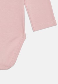 Lys rosa langermet bodysuit laget av myk bomull, med en glatt tekstur og tettsittende passform, med trykknapp nederst.
