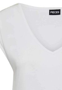 T-shirt blanc en V fabriqué à partir d'un tissu doux et léger. Il présente des manches courtes légèrement amples et une finition lisse avec des détails de couture minimaux.