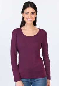 Langärmliges Oberteil aus dunkellila Stoff mit einem strukturierten Rautenmuster, das einen Rundhalsausschnitt und einen dezente gewellten Saum aufweist.