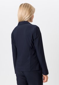 Marineblauwe blazer van gladde stof, met een getailleerde pasvorm, reverskraag en lange mouwen. Achteraanzicht toont het naadloze ontwerp.
