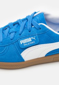 Blaue Wildledersneaker mit weißen Akzenten, strukturierten Schnürsenkeln und Gummisohle. Puma-Branding an der Seite und auf der Zunge. Sauberes, sportliches Design.