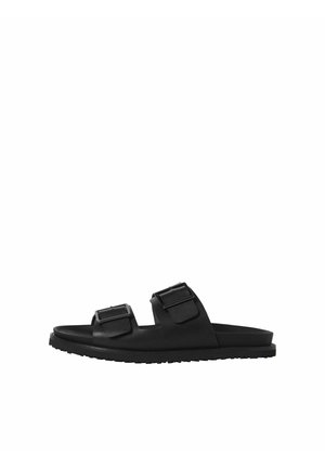 Sandale noire à bout ouvert avec deux larges brides réglables et boucles, semelle plate avec grip texturé, vue de côté sur fond blanc.